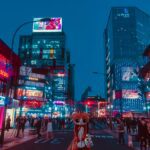 A street in Myeongdong, Seoul at night showcasing neon lights and people shopping.