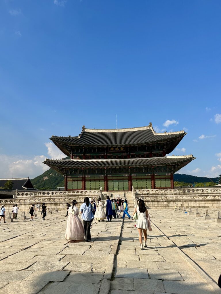The main palace building at Gyeongbokgung Palace in Seoul, with tourists dressed in hanbok.